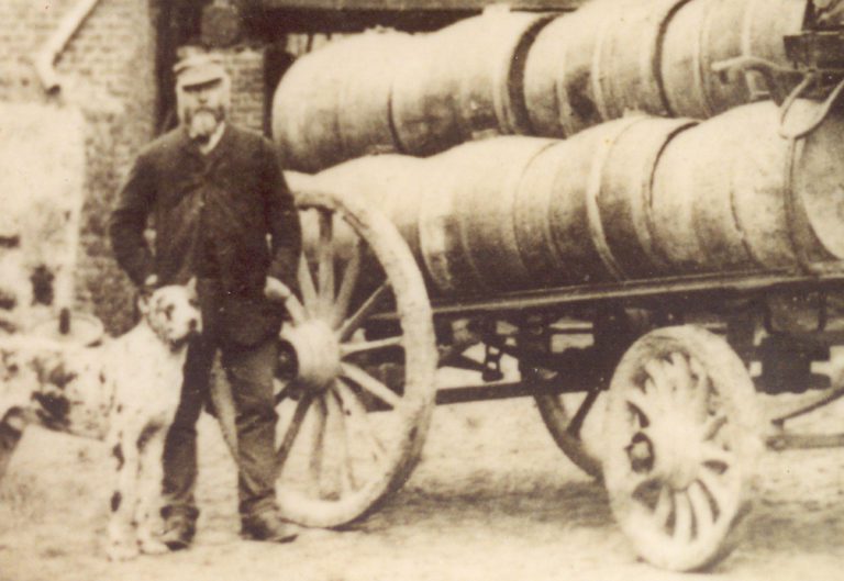 Jules Lefebvre  (1ère génération et créateur de la Brasserie Lefebvre) pose à côté d'une charrette en bois portant des fûts en bois. 